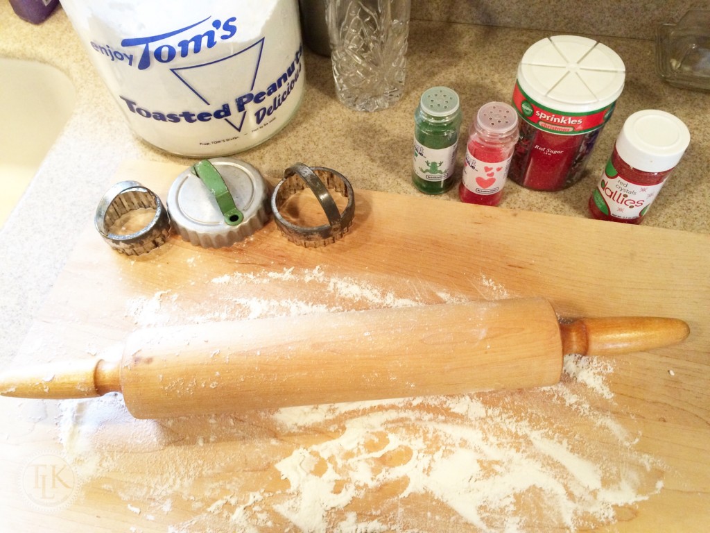 Tools for making sugar cookies include a rolling pin, cookie cutters and colored sugar