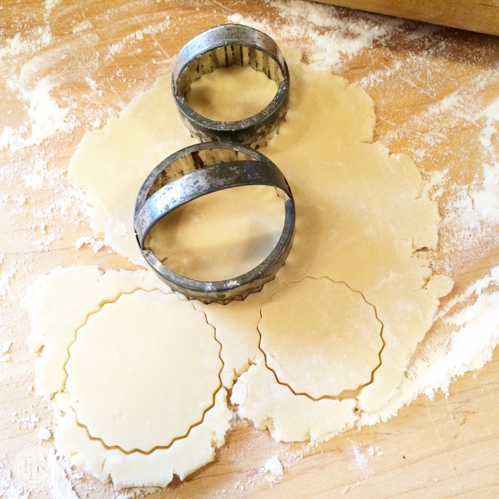 Cutting cookie shapes out of dough with antique cookie cutters